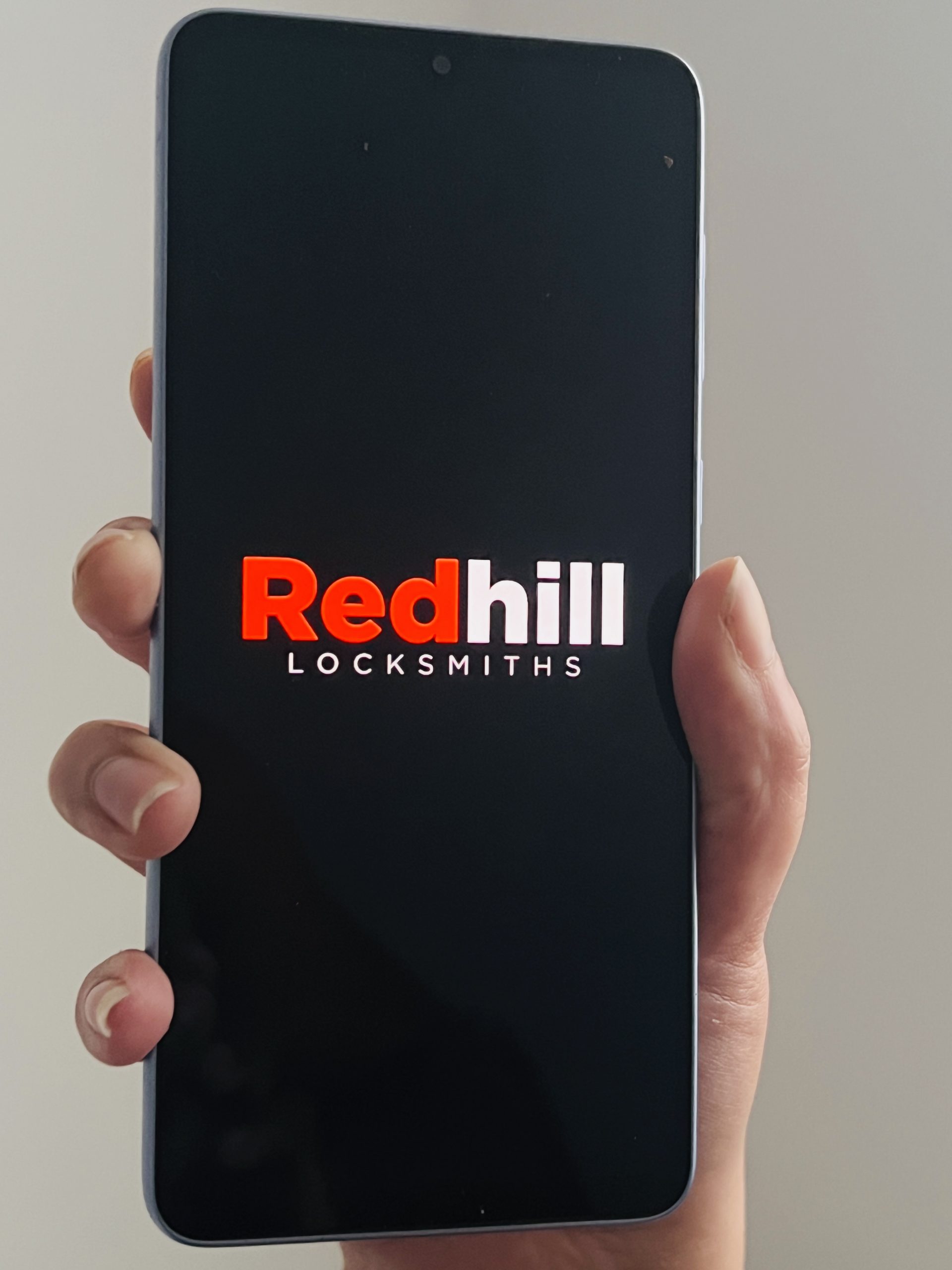 hand holding a mobile phone for local locksmith in redhill locksmiths ltd in rh1